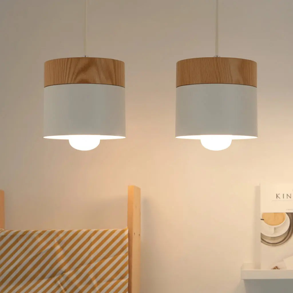 Two pendant lights with wooden and white shades hanging against a neutral wall.