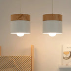 Two pendant lights with wooden and white shades hanging against a neutral wall.