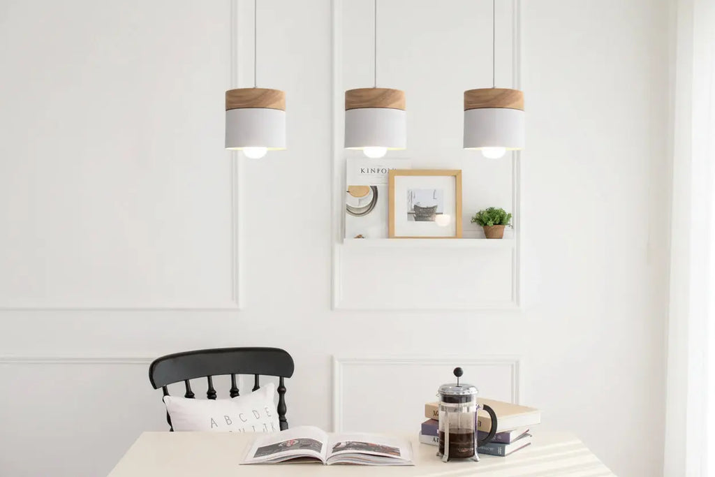 Three pendant lights hanging above a dining table with a chair and books in the foreground.