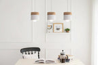 Three pendant lights hanging above a dining table with a chair and books in the foreground.