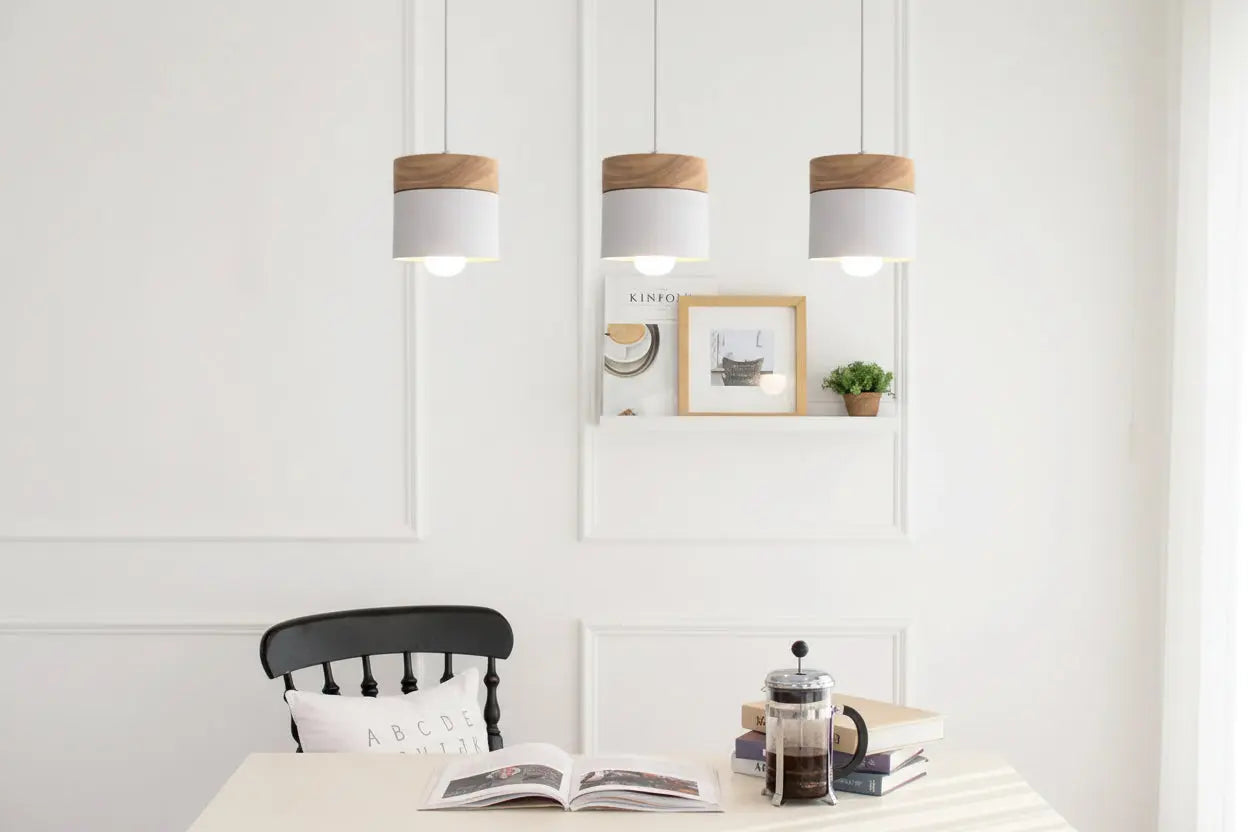 Three pendant lights hanging above a dining table with a chair and books in the foreground.