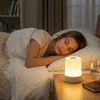 Woman sleeping in bed with a night lamp on a bedside table.